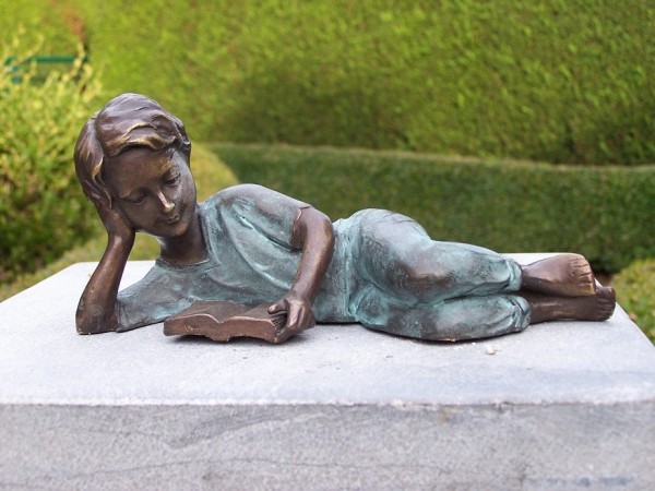 Mädchen Josephine liest im liegen ein Buch als Bronzeskulptur